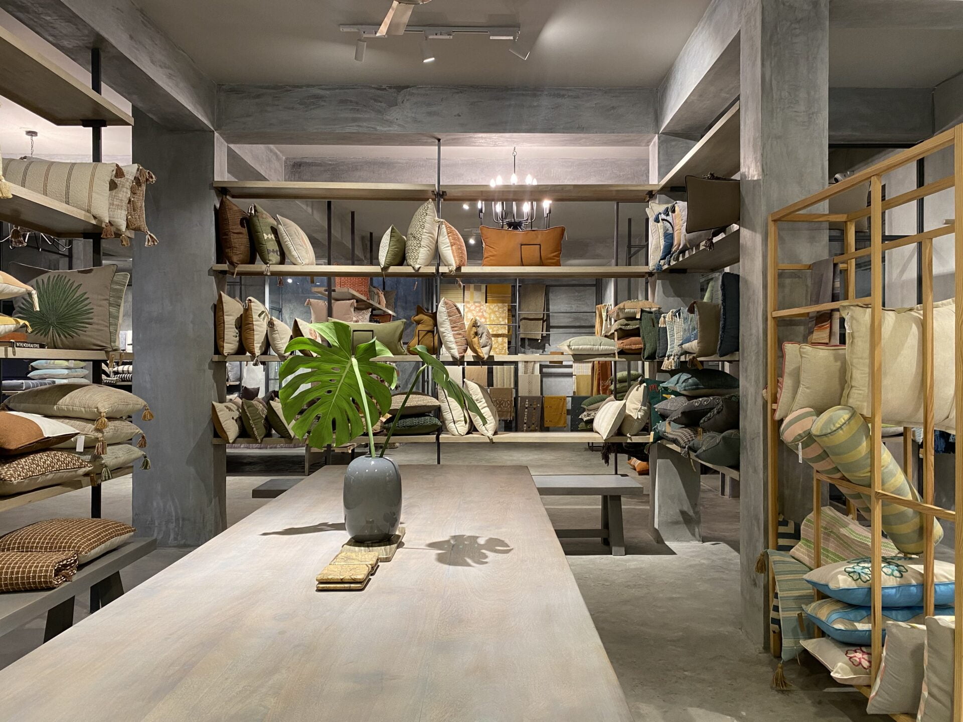 Center stage: A substantial wooden table anchors the retail floor, surrounded by rows of colorful textiles displayed on custom industrial shelving.